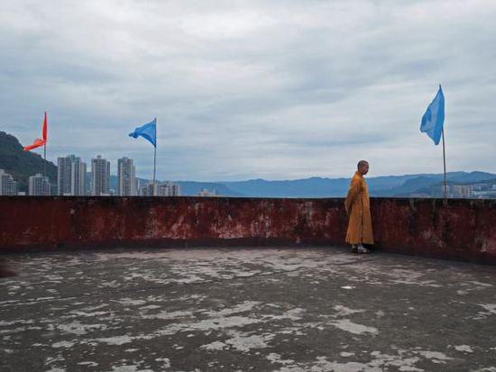 一名和尚在万州弥陀禅院眺望万州城。许海峰