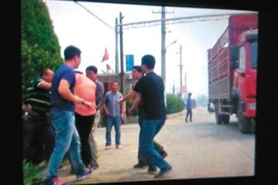 记者(粉色衣服者)遭多名男子抢夺相机。据人民网