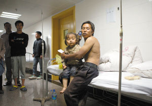 昨晚，一名惊魂未定的小女孩在父亲的陪伴下在县人民医院接受治疗 曲鸣飞 资渔 摄