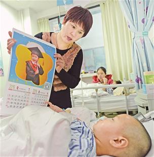 图为：妈妈拿着挂历给小思语看。看到挂历上自己的照片，她暂时忘记了疼痛 楚天都市报记者王永胜摄