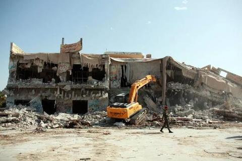 2011年10月30日,在利比亚首都的黎波里,挖掘机在拆除象征卡扎菲权力的阿齐齐亚兵营。(新华社发 哈姆扎·图尔基亚摄)