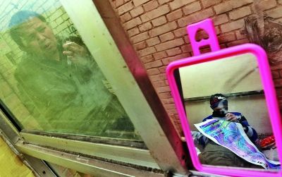 　　老吴在屋外抽烟时，也时不时透过窗子看着虚弱的儿子吴帅 摄/法制晚报记者 刘畅