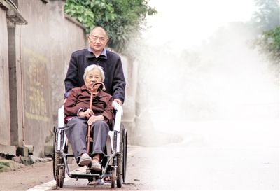 　昨晨，小雨，邹开新推着冉文先往江津贾嗣镇民政办走去。  　　本版图/重庆晨报记者 杨野